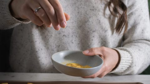 Marie-Eve saupoudre de la levure nutritionnelle sur des légumes
