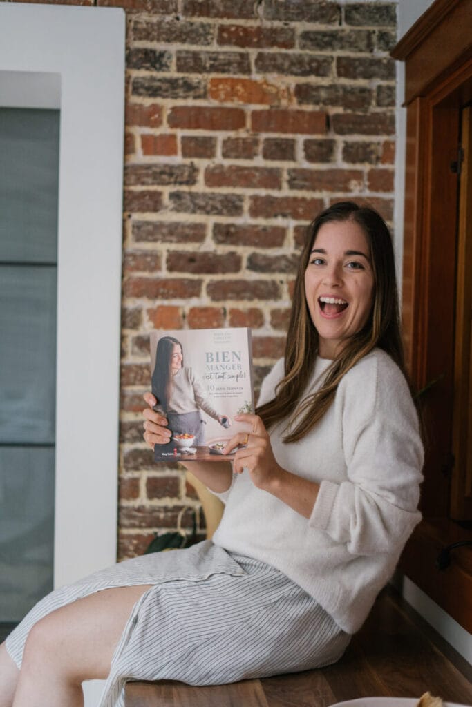 marie-eve dans la cuisine qui tient son livre Bien manger simplement et sourit